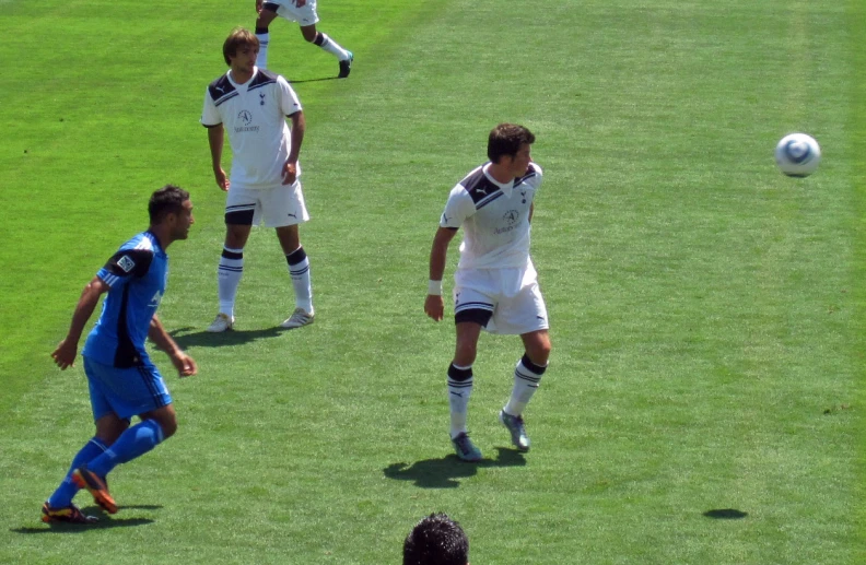 three men playing soccer against each other on grass