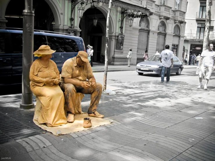 a man and woman in yellow dress sitting on top of some sculptures