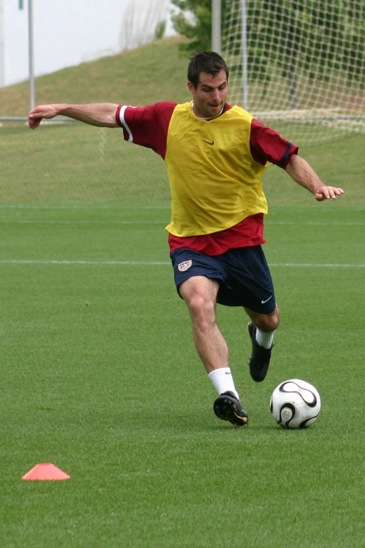 man wearing yellow and red jersey playing soccer on grass