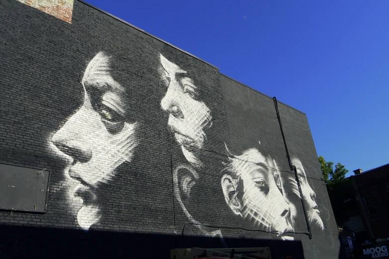 large picture on side of brick building featuring men with different faces