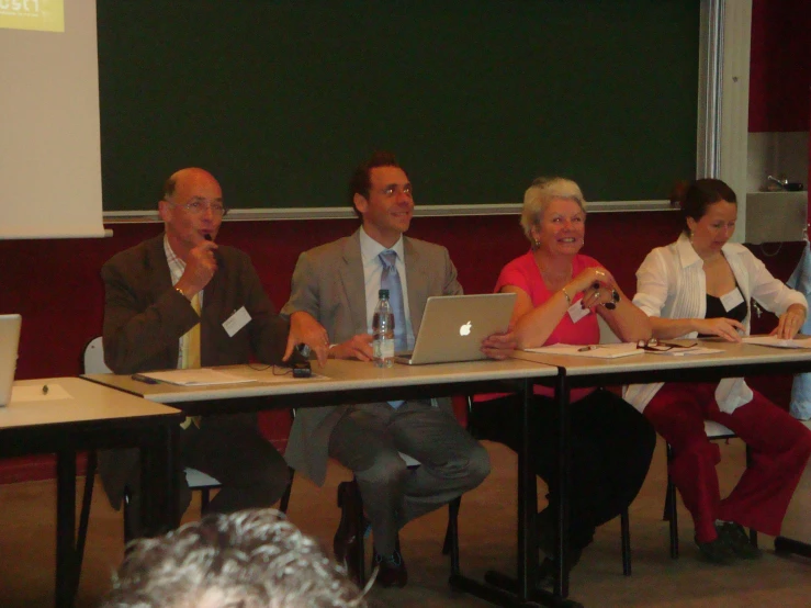 five business people sitting at a table with their laptops