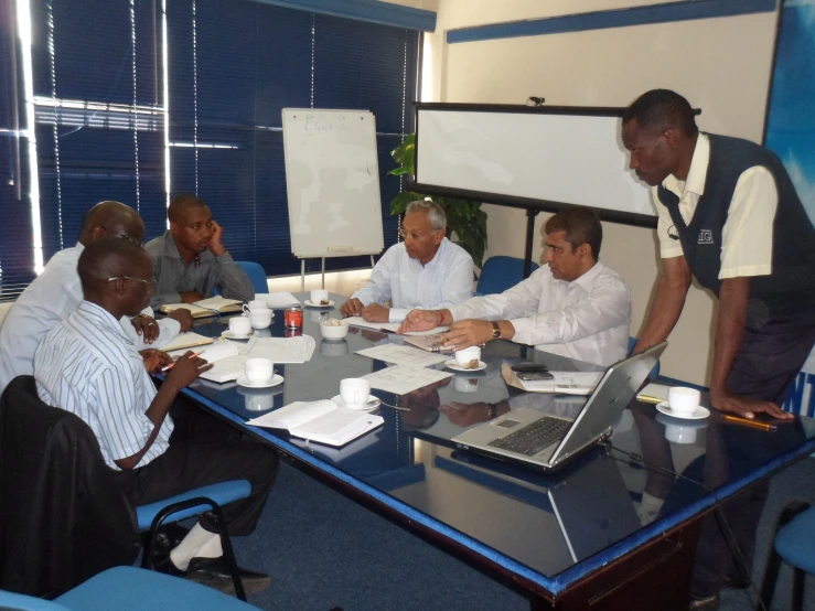 a group of people sitting at a table together with their laptops