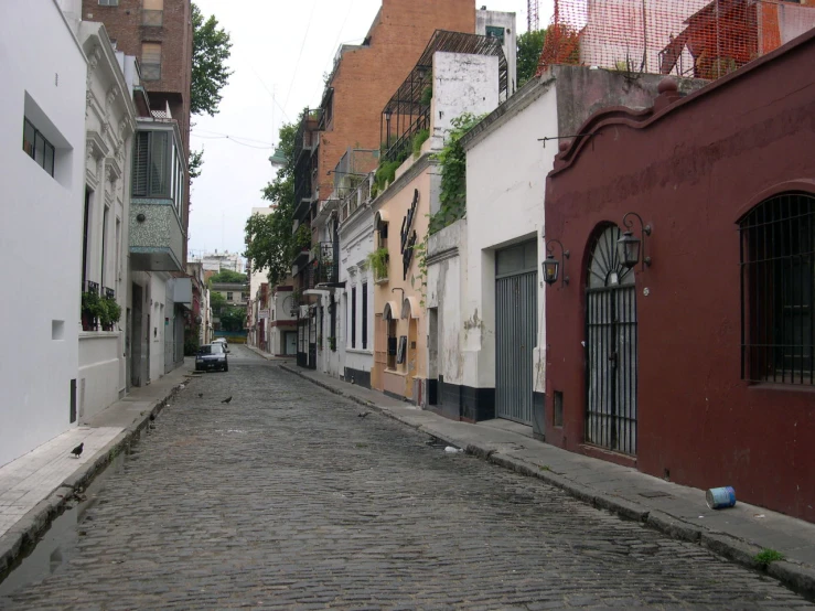 the narrow cobblestone street in the town features multiple colored buildings