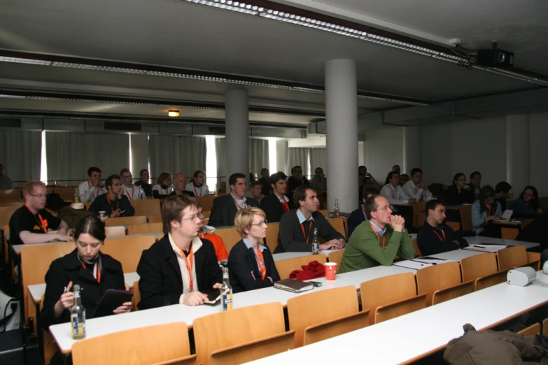 a room full of people listening to speakers