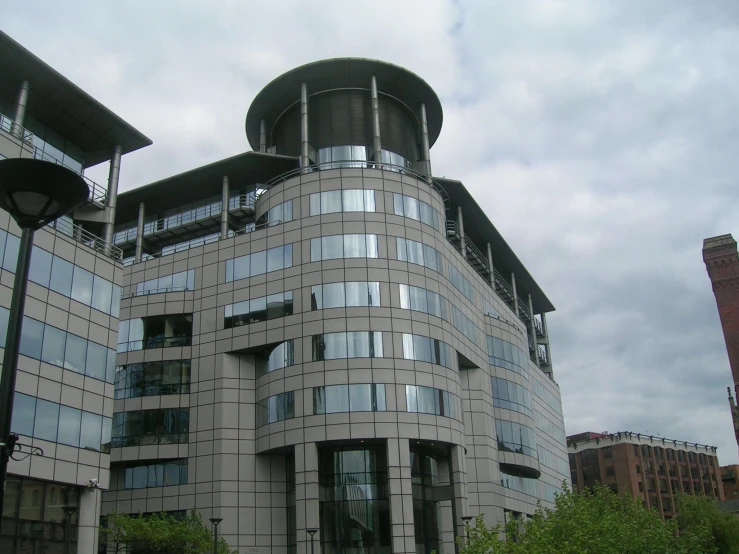 a gray building with a round top next to a park