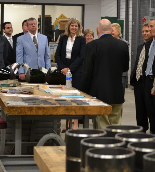 several people stand around a table with many items on it