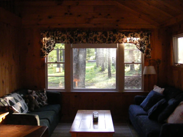 living room with couches and window looking out onto wooded area