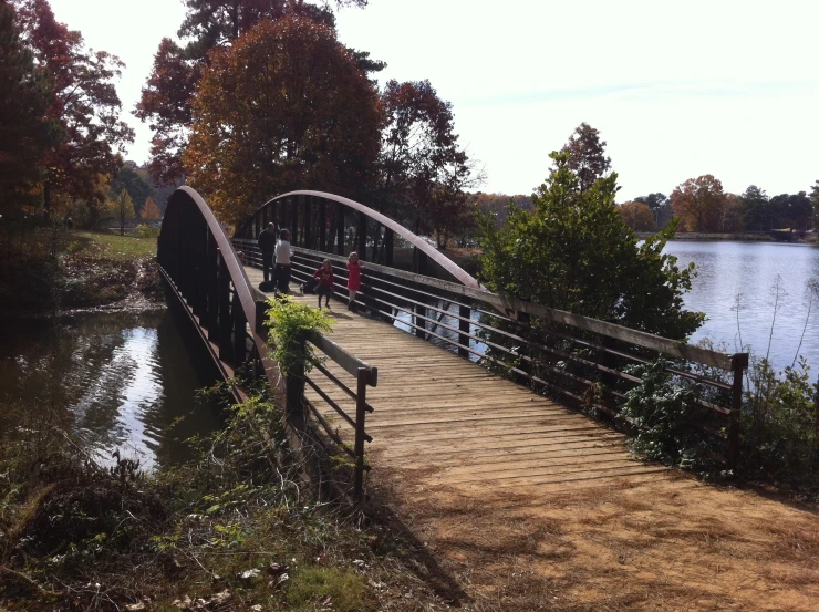 a walkway leading across a lake with an umbrella on the bridge