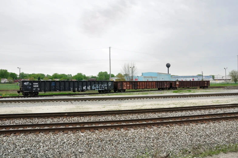 an abandoned cargo train on the tracks by the farm