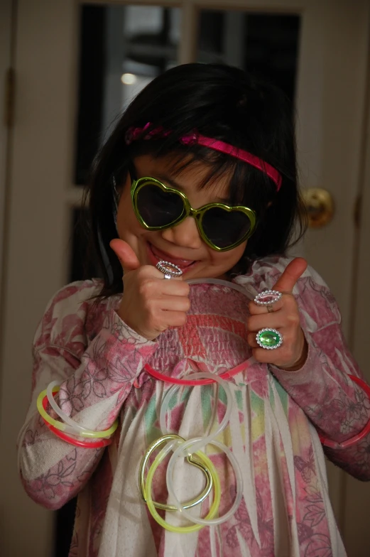 a little girl is wearing green goggles and some rings