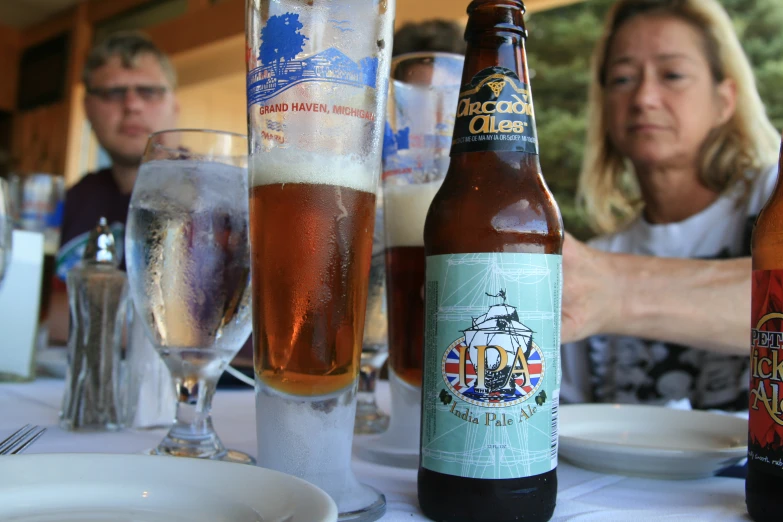 a woman standing behind a table filled with bottles of beer