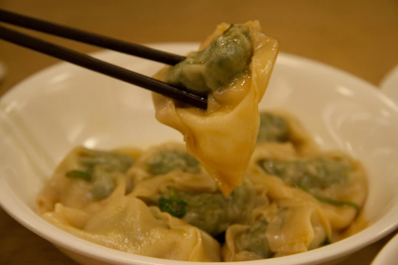 a bowl of chinese food is being lifted with chopsticks