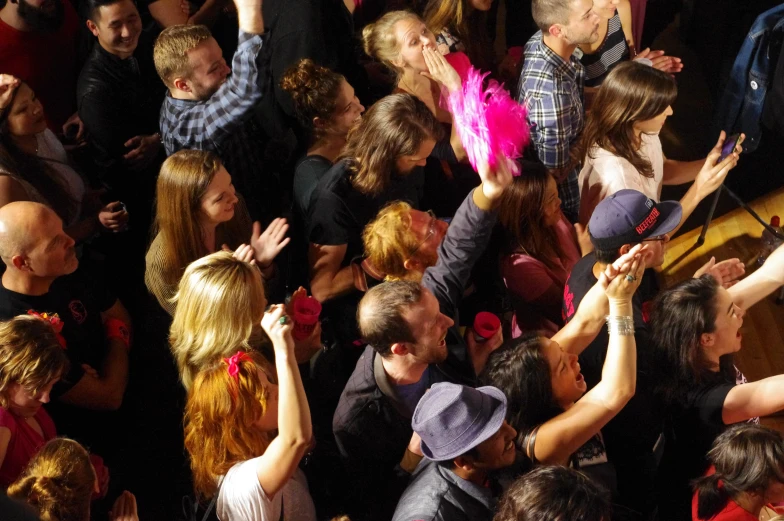a crowd of people in a room holding hands up
