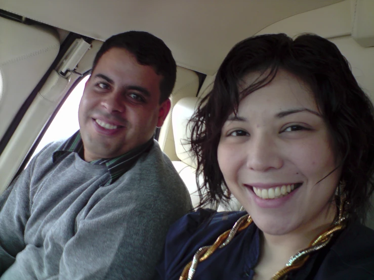 a smiling couple in a vehicle near the window