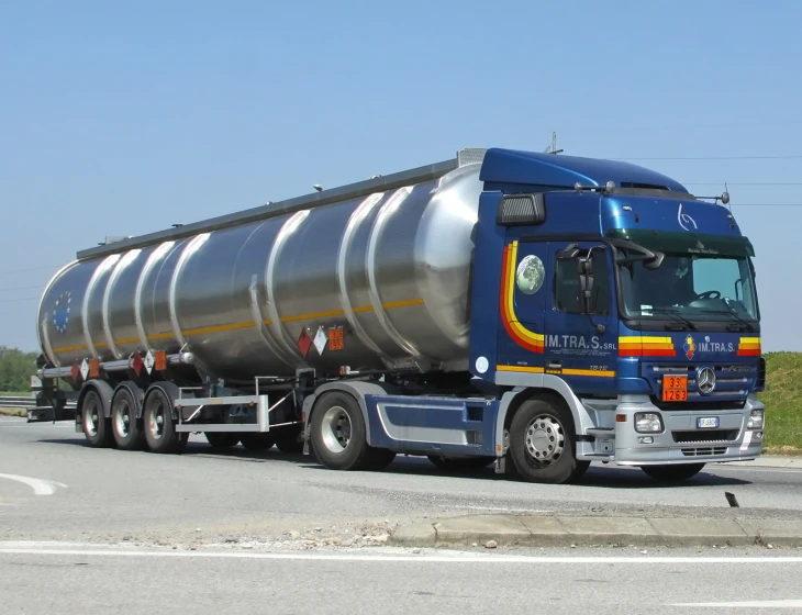 a large truck on the road with a steel tanker trailer