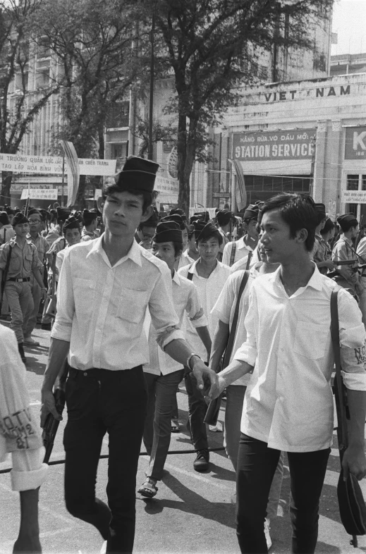 men in uniforms walk down a busy city street