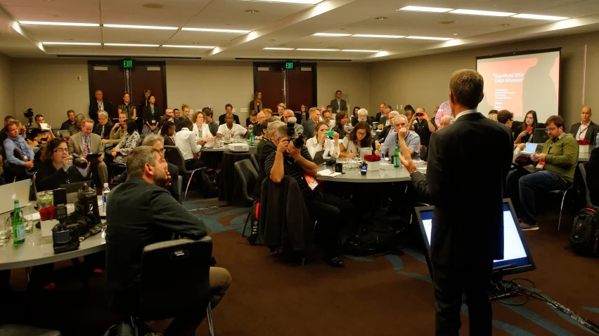 a conference is full of people and has a man standing in front of him