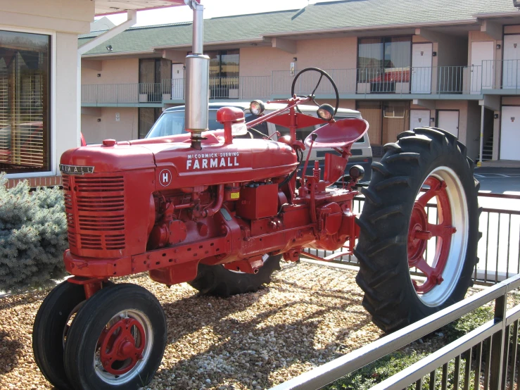 a red farmall parked in front of a el