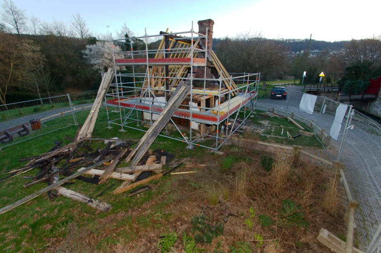 a house under construction on a hill near a fence