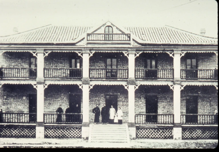 an old house with people standing on the porch
