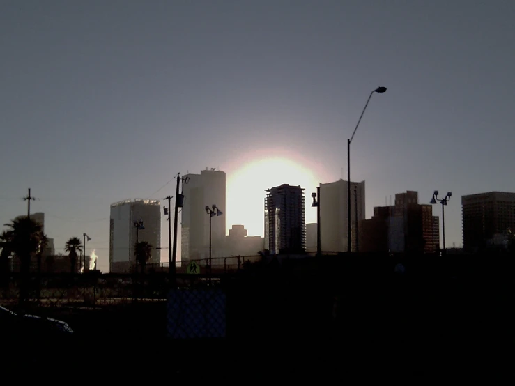 a view of the sun rising behind a city skyline