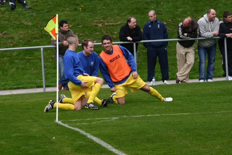 some soccer players laying on a field while a group of people watch