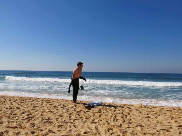 man standing on beach with surfboard in hand