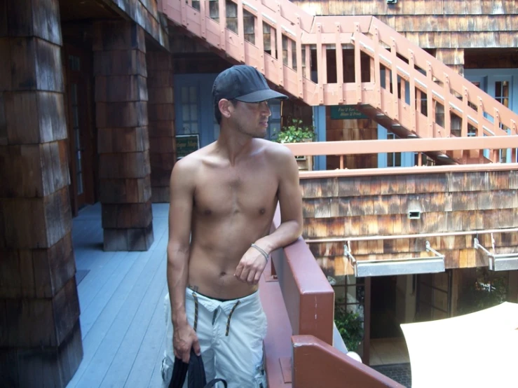 a shirtless man standing on a deck in front of a building