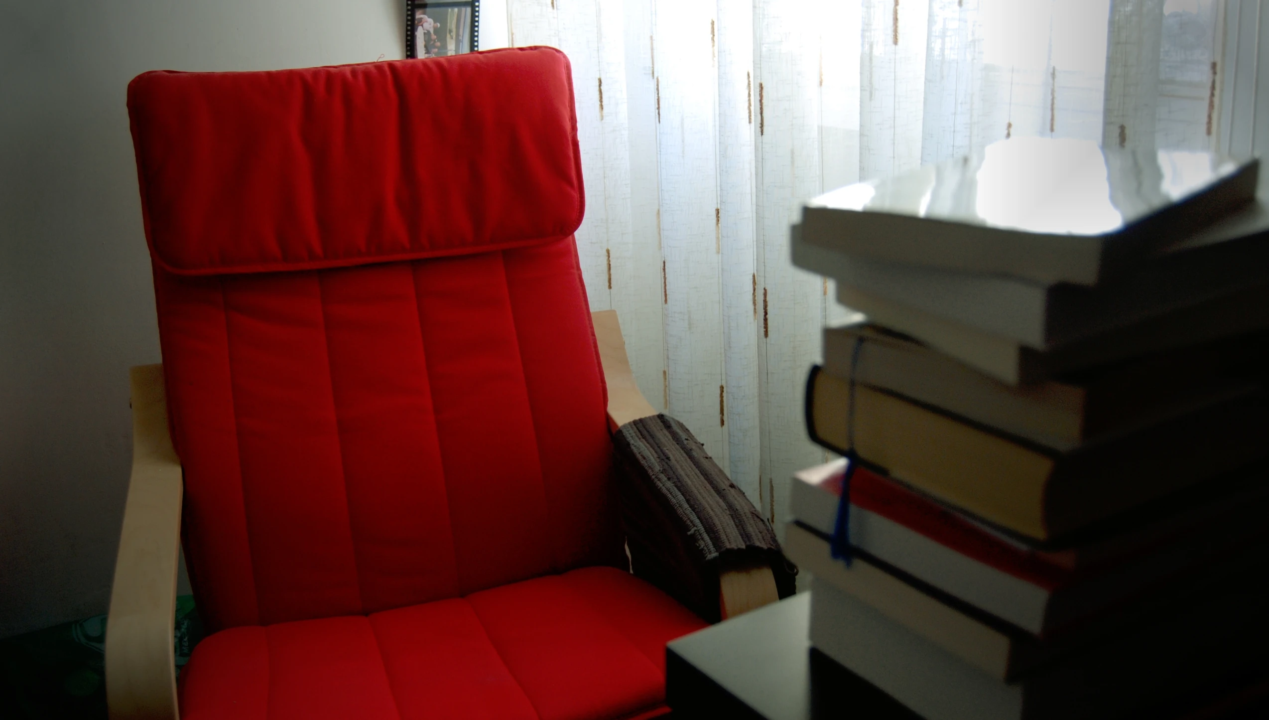 a stack of books next to a red chair