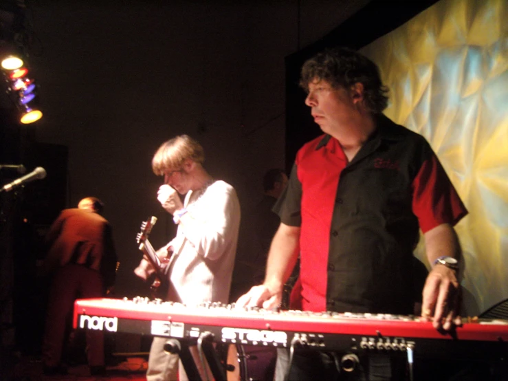 the two men are playing instruments together in front of microphones