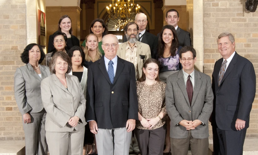 several men and women pose for a picture in front of an ornate door