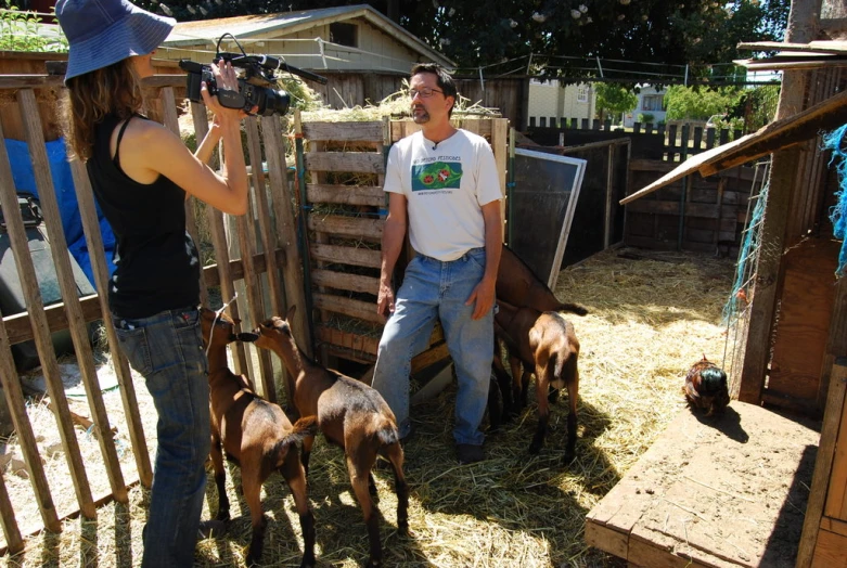 a woman pographs a man while others are petting some small animals