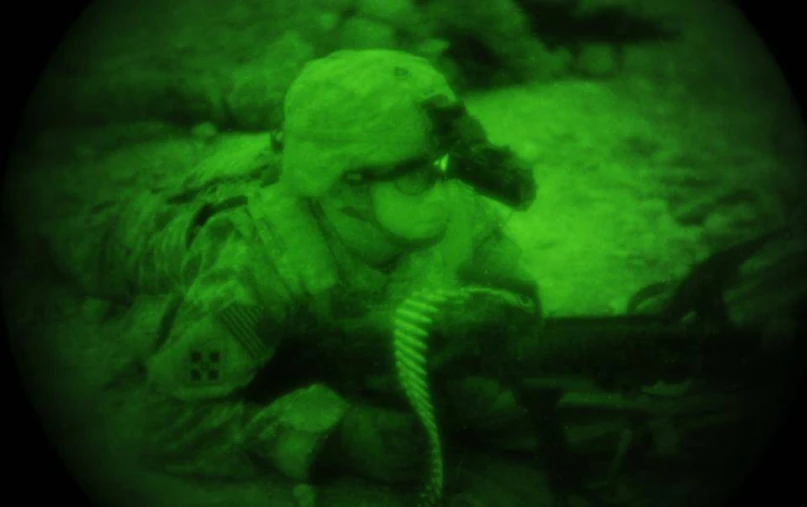 a soldier kneeling in the desert with a gun