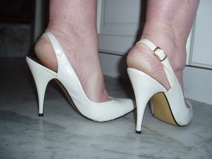 a woman's feet with white shoes and heels