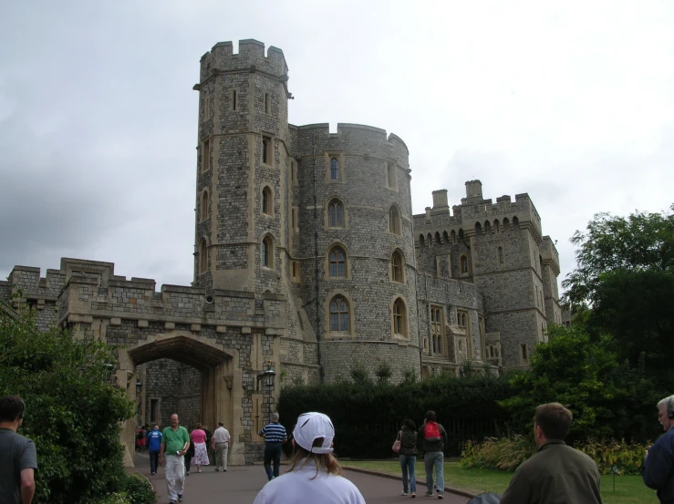 people are walking down the path towards an old castle