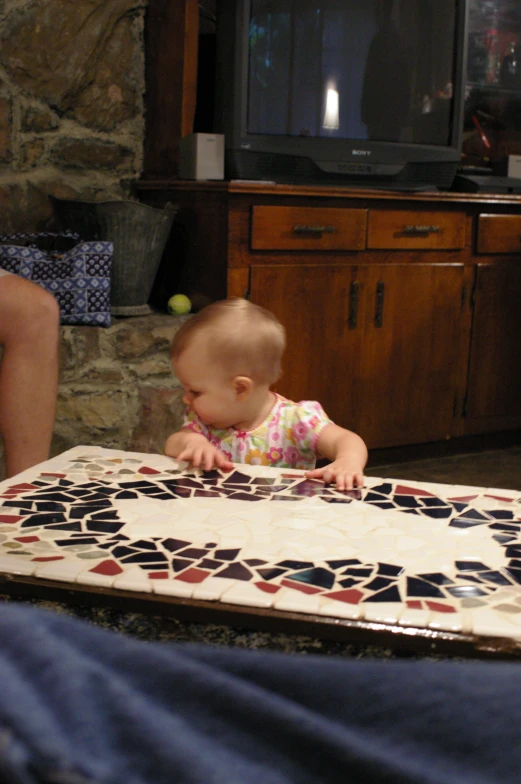 a baby is playing on a multicolored mosaic rug