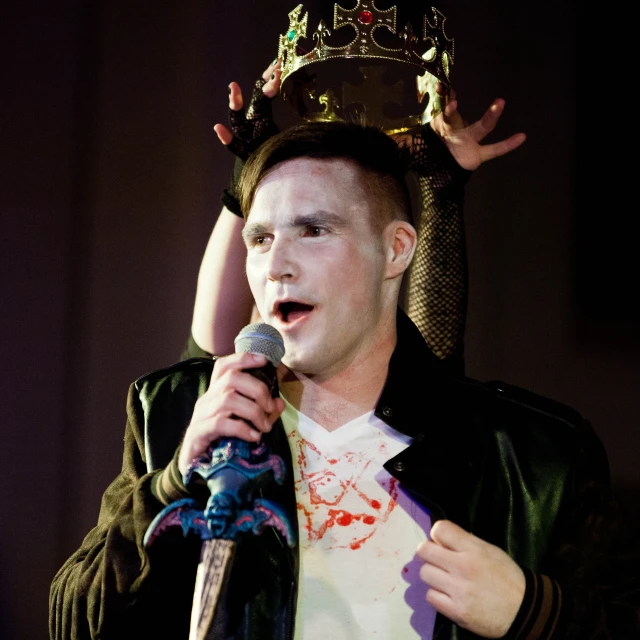 a man wearing a crown is singing into a microphone