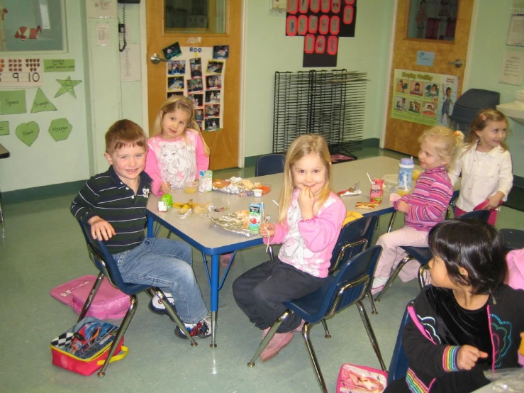 five children sitting at a table eating lunch