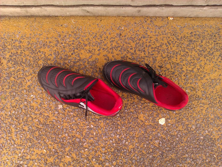 there is a red and black pair of shoes on the sidewalk