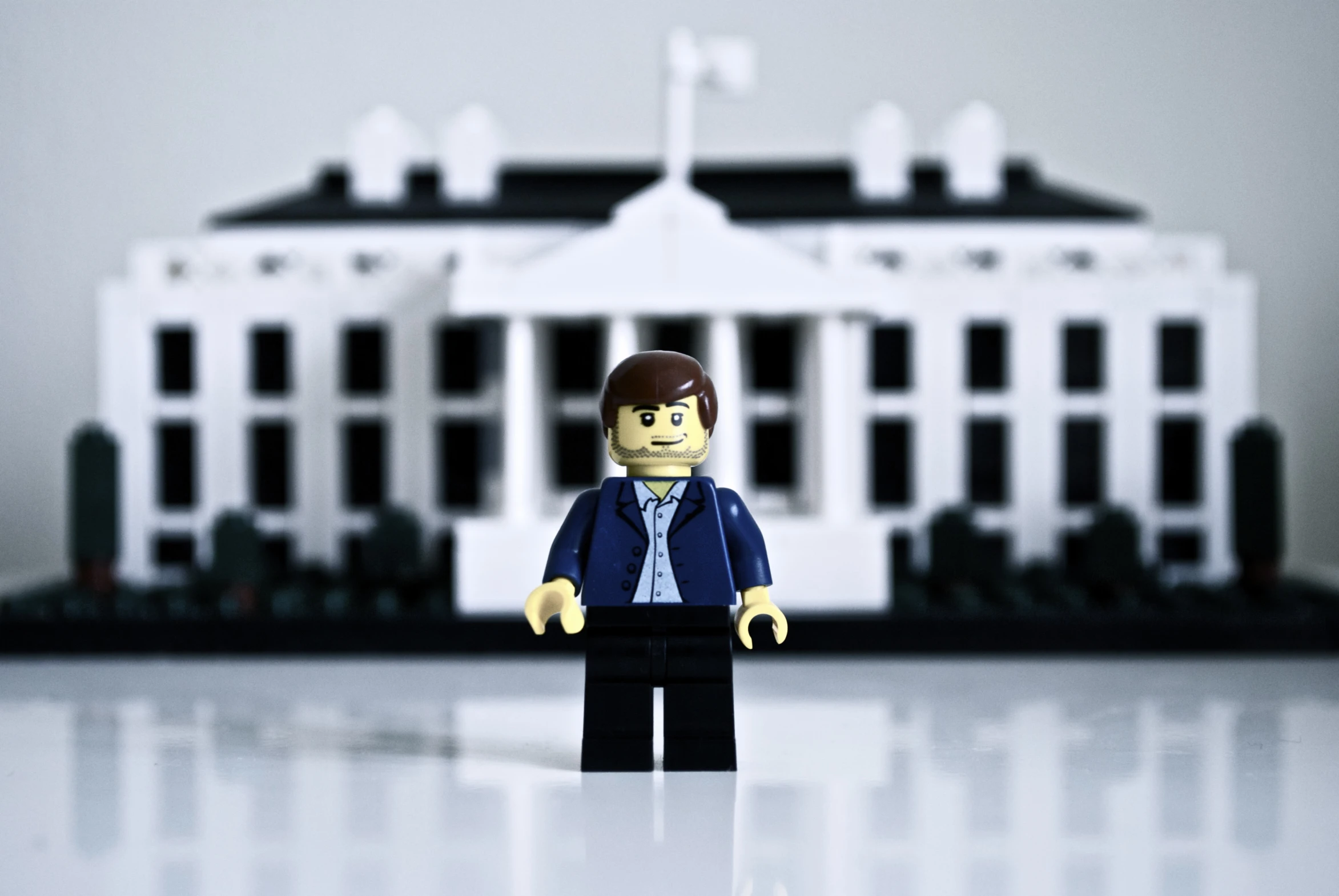 a lego person stands near a model of the white house