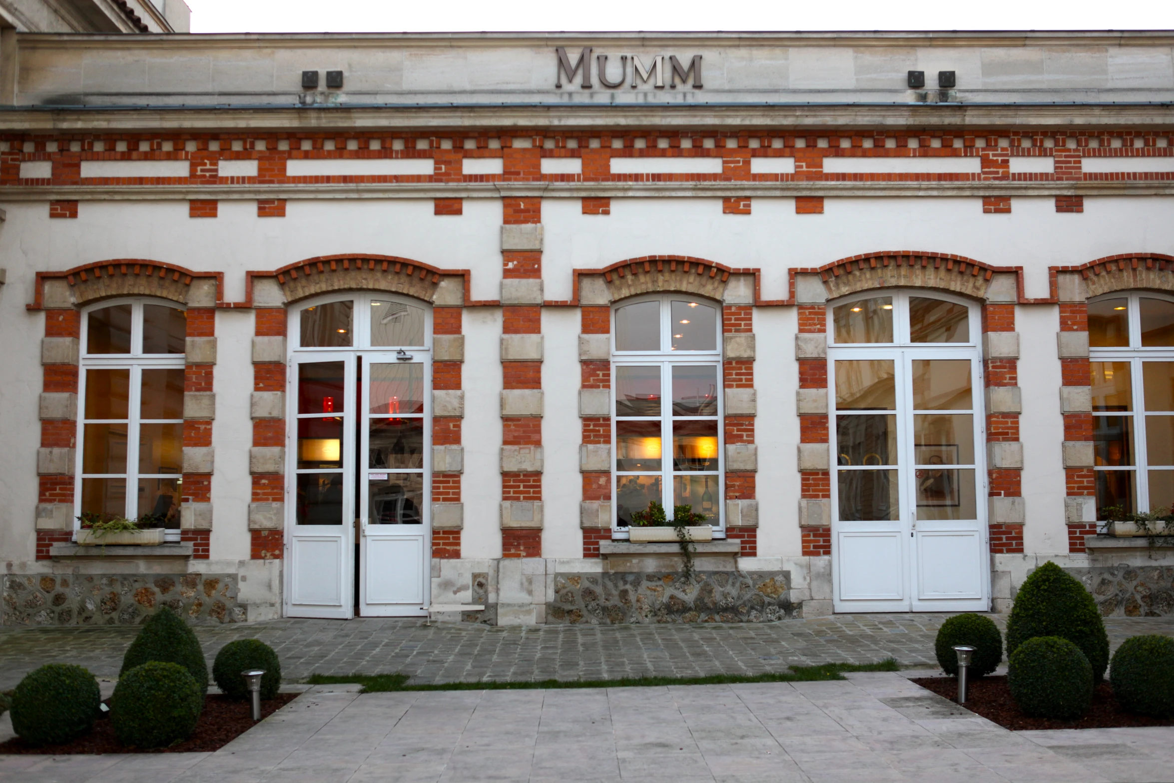 the building is white and brick with two double doors