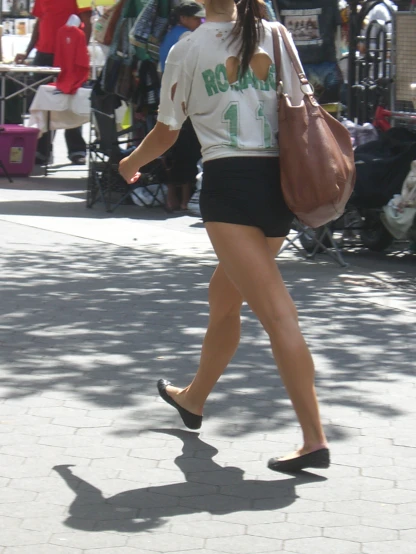 a woman walking down a street holding a brown bag