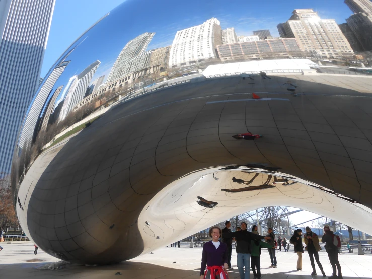 several people standing around an outdoor structure with a mirrored top