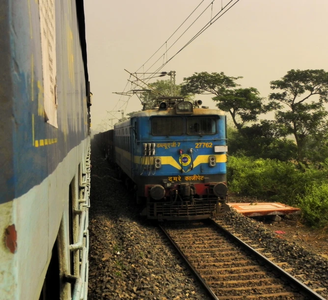 blue train sitting on tracks next to trees