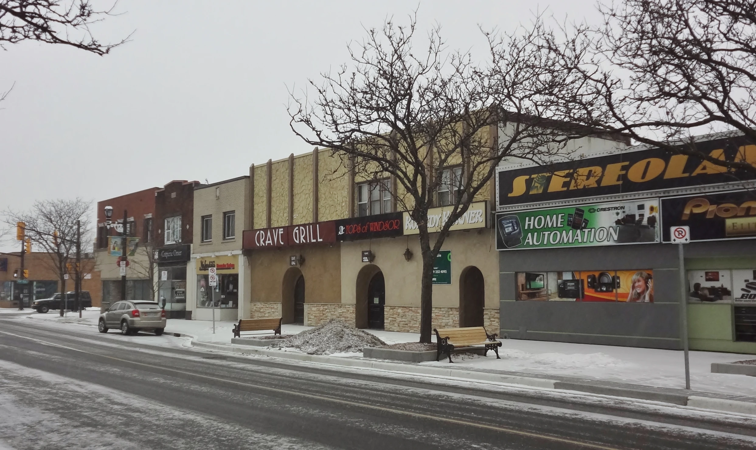 snow is piled on the street corner by shops