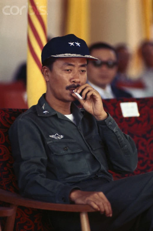 a man sitting in front of a group of people on a red chair