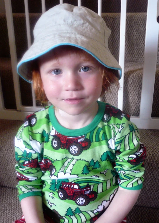 a child is wearing a hat while sitting on the ground