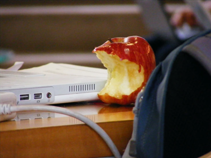 a red apple sitting on top of a laptop computer