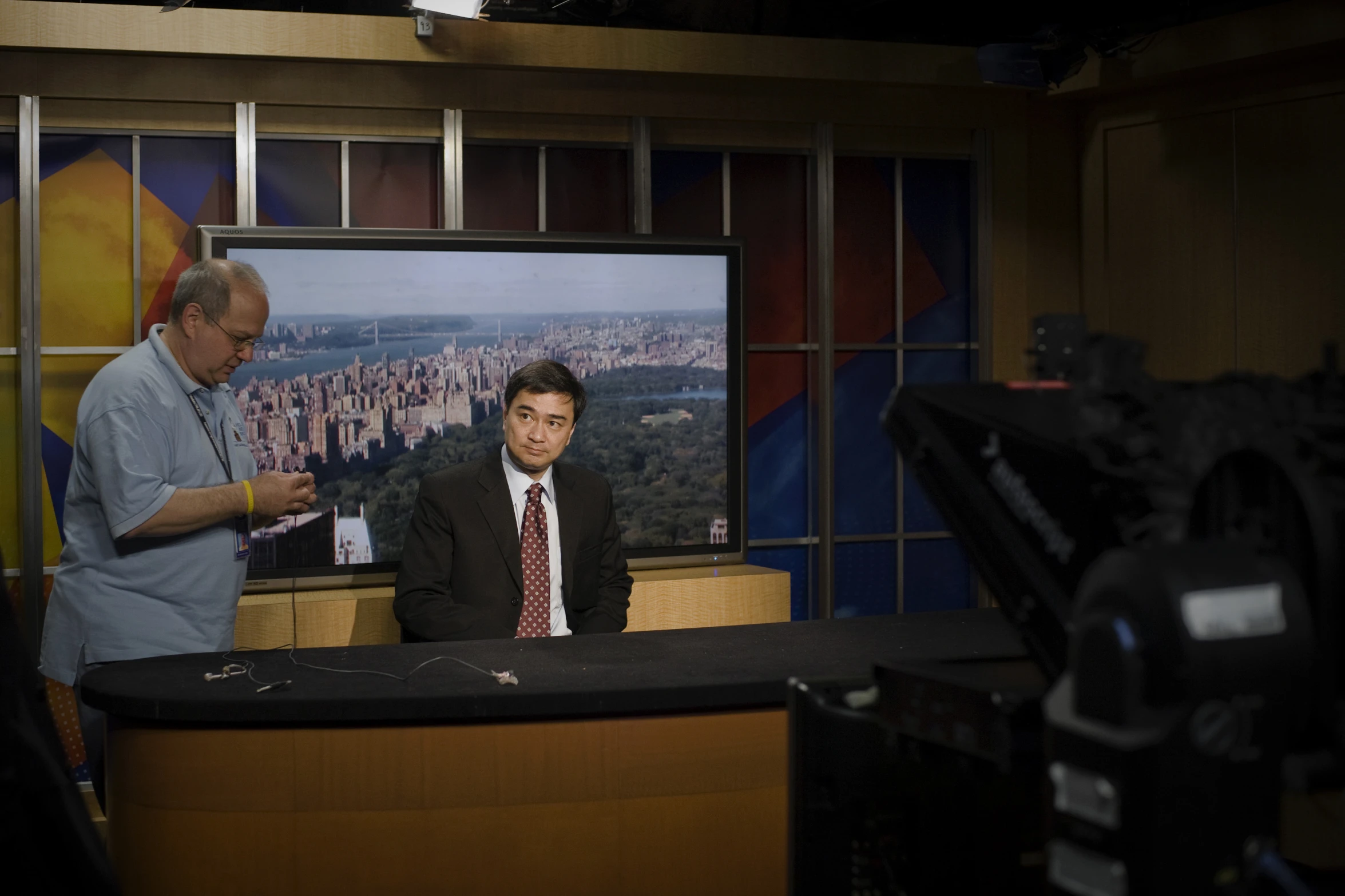 two men stand next to a television set