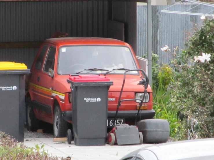 a red van and a red trash can on a curb